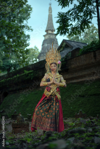 Pretty Asian woman wearing an ancient Traditional Khmer Cambodian Apsara dress costume shows the ghost a typical fairy Apsara. © pomphotothailand