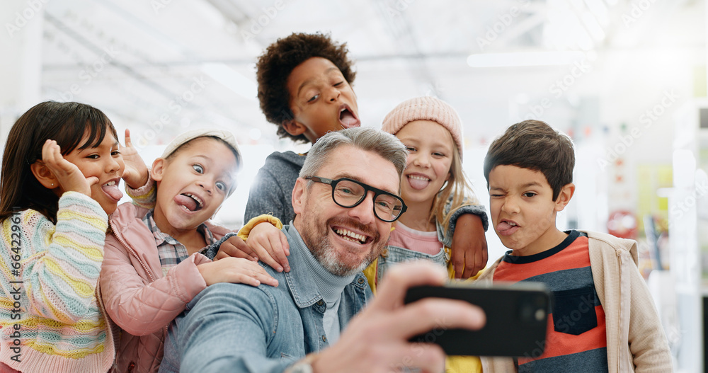 Obraz premium Selfie, children and teacher with funny face, smile and picture with educator, excited and happy. Kids, internet and cellphone for technology, online and memories for school, classroom or diversity