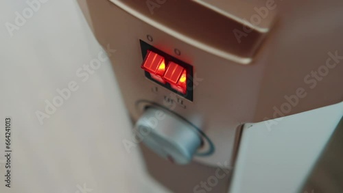 Turning on and adjusting the temperature on the electric heater panel, close-up. The concept of heating a room without heating during the cold season. photo