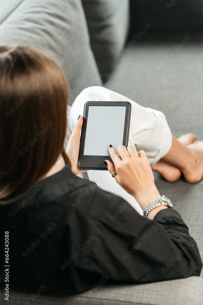 Young woman sitting the couch with an e-book Young woman sitting the couch with an e-book
