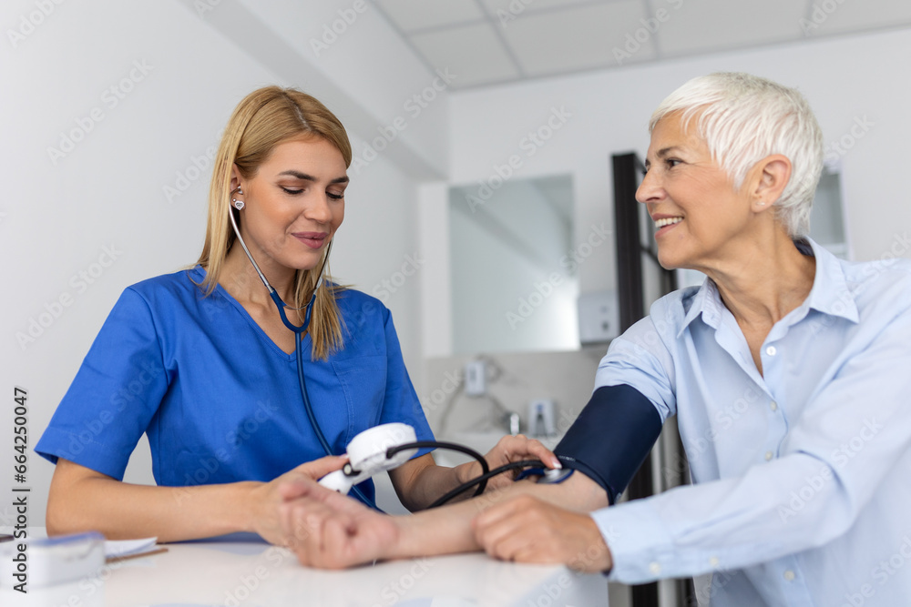 Fototapeta premium Measuring blood pressure. Senior woman have a visit with female doctor in modern clinic. Measuring blood pressure. Pressure gauge. Hypertension and high heart rate