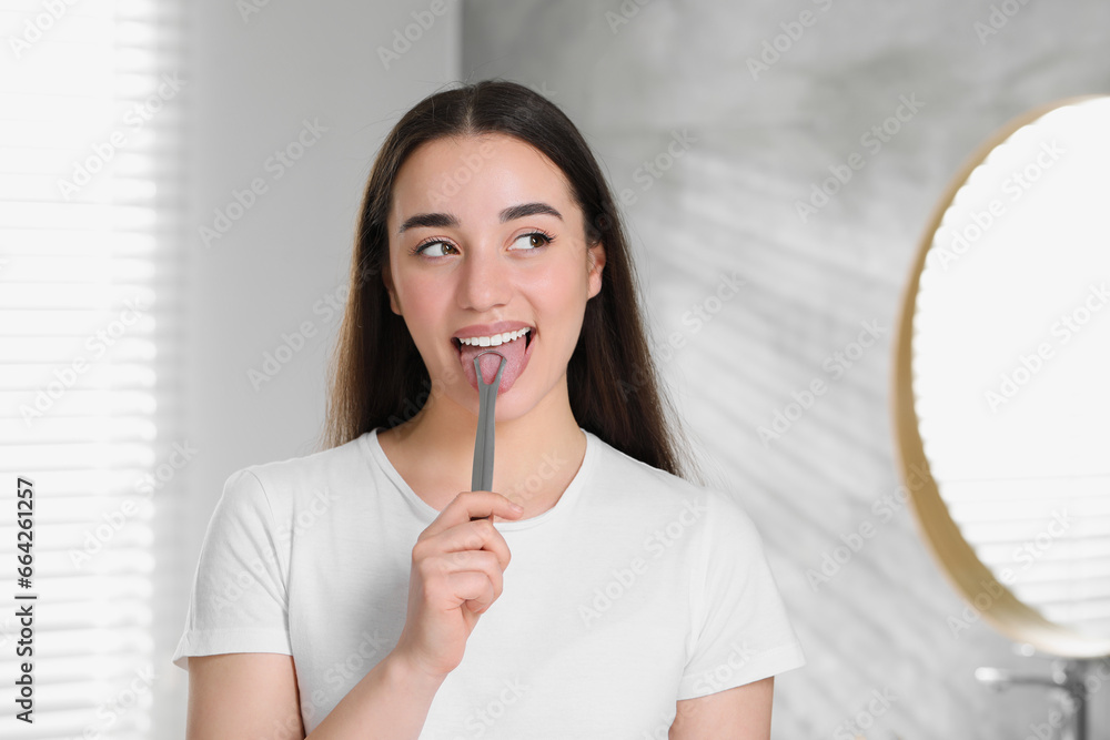 Happy woman brushing her tongue with cleaner in bathroom Happy woman brushing her tongue with cleaner in bathroom