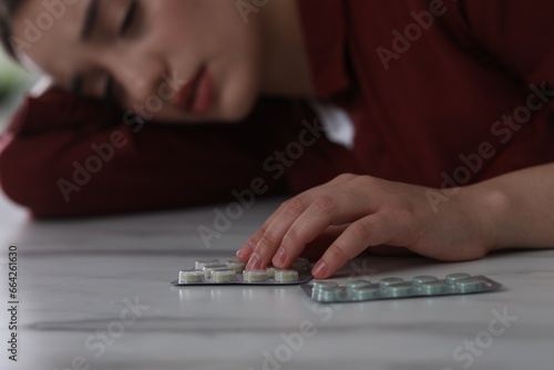 Woman with antidepressant pills sleeping at white marble table, selective focus photo
