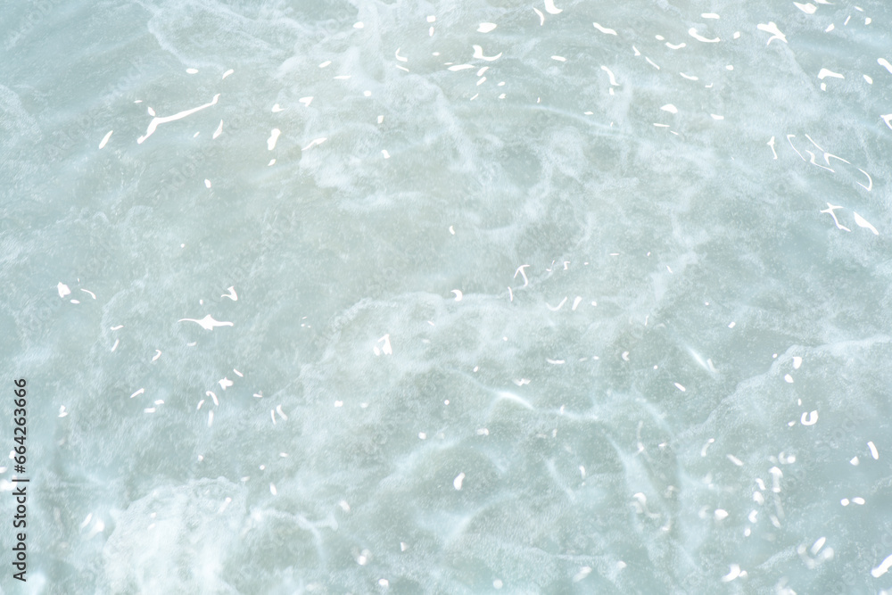 Obraz premium Bluewater waves on the surface ripples blurred. Defocus blurred transparent blue colored clear calm water surface texture with splash and bubbles. Water waves with shining pattern texture background.