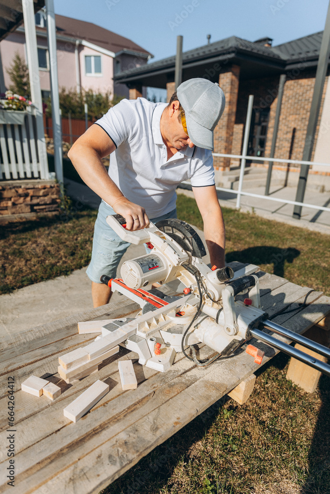 male carpenter cuts a wooden board with an electric saw at home. builder. male carpenter cuts a wooden board with an electric saw at home. builder.