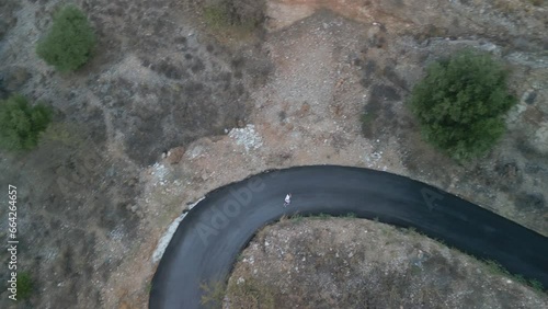 Kid running on windy tarmac road in Mediterranean landscape. 