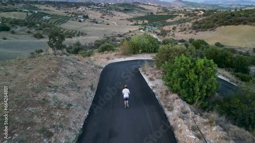 Kid running on windy tarmac road in Mediterranean landscape. 