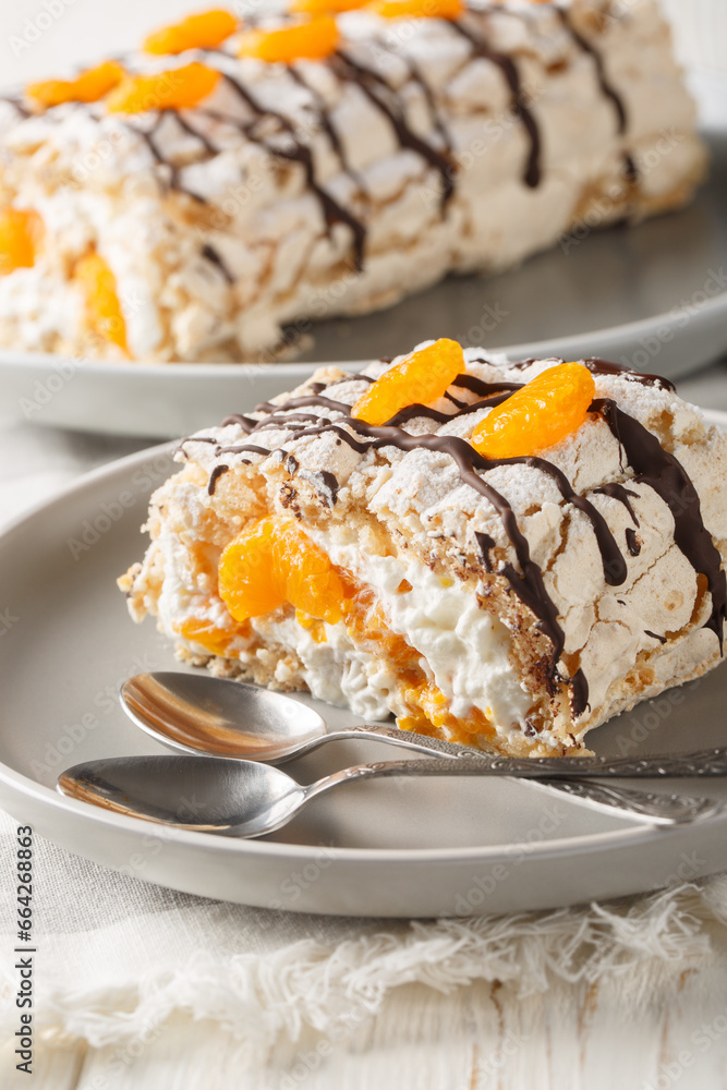 Swedish dessert Budapest roll filled with whipped cream and mandarins close-up in a plate on the table. Vertical Swedish dessert Budapest roll filled with whipped cream and mandarins close-up in a plate on the table. Vertical