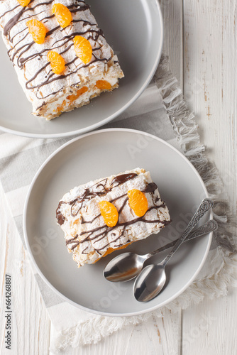 Photography Swedish dessert Budapest roll filled with whipped cream and mandarins close-up in a plate on the table