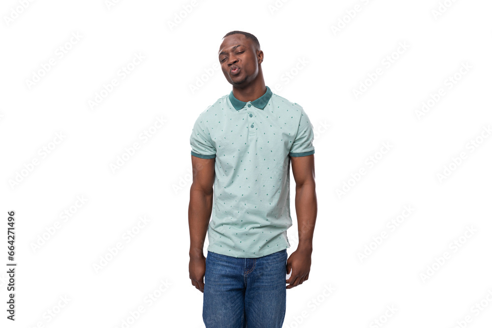 young shy african man dressed in a t-shirt and jeans stands thoughtfully young shy african man dressed in a t-shirt and jeans stands thoughtfully