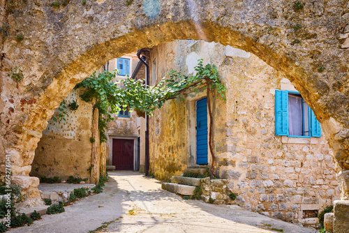 Croatia Istria. Ancient abandoned medieval town Plomin. Old stone street with ruined walls houses and stairs overgrown by ivy plants