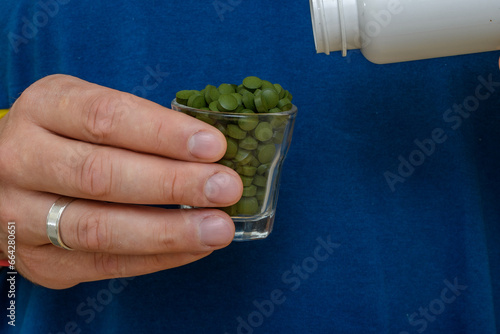 Kieliszek pełny zielonych tabletek, suplementy diety