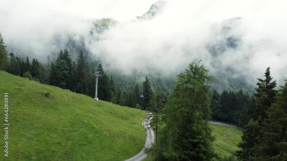 Steep cable car in the alps in Austria surrounded by green grass and a forrest during a cloudy day Steep cable car in the alps in Austria surrounded by green grass and a forrest during a cloudy day