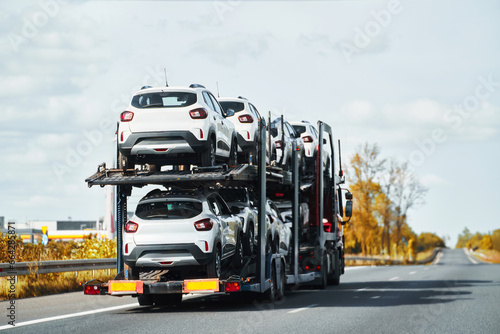 Tow truck with a cars on the highway road. Tow truck transporting car on the autobahn. Car service transportation concept. Roadside Rescue. © AlexGo