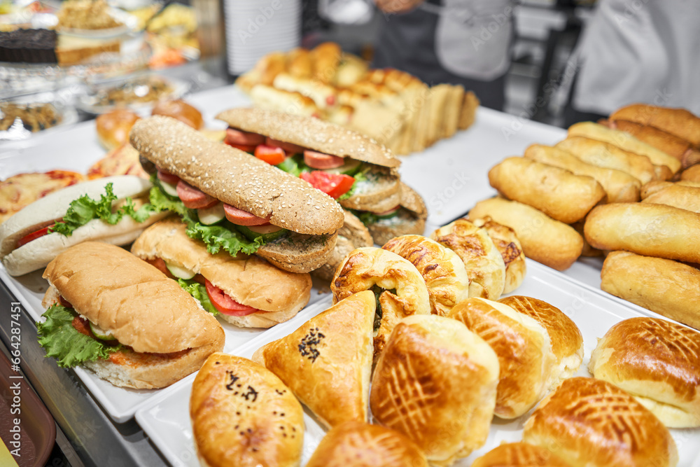 Fresh sandwiches, pies and pizza to choose from in the window of a cafe, buffet or self-service cafe. Croissant with ham and cheese. Hot pastries lie on the shelf in the cafe. Buns in the store.