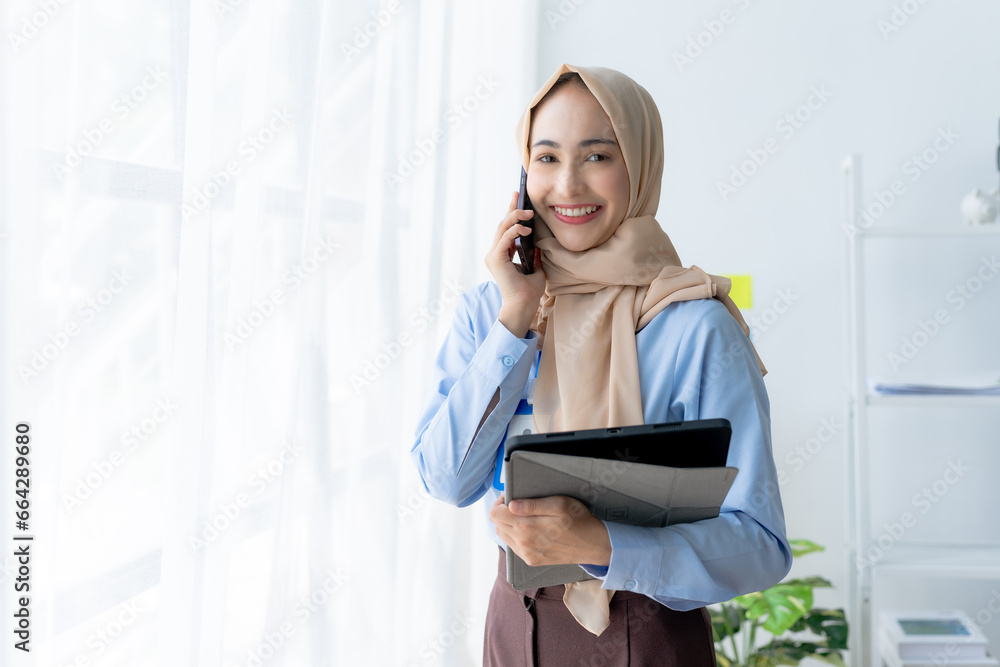 Muslim businesswoman making a professional phone call in her office. Muslim businesswoman making a professional phone call in her office.