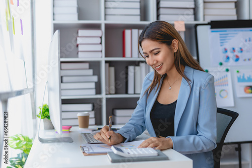 Tablou pe pânză Asian businesswoman using laptop computer and paperworks with planning working on financial document, tax, exchange, accounting and Financial advisor
