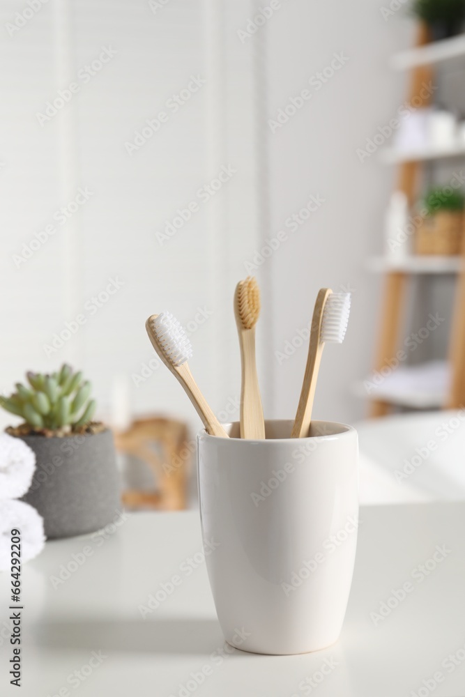 Holder with bamboo toothbrushes on white countertop in bathroom Holder with bamboo toothbrushes on white countertop in bathroom