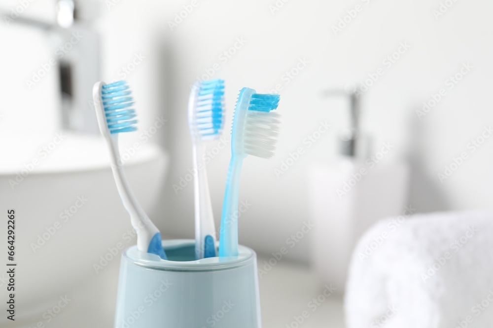 Plastic toothbrushes in holder on blurred background, closeup. Space for text Plastic toothbrushes in holder on blurred background, closeup. Space for text