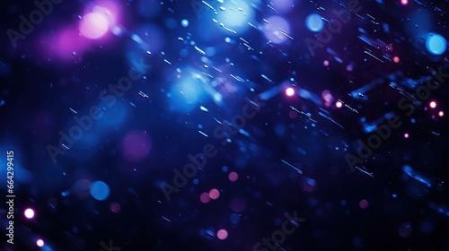 Blurry flecks of blue and purple hues dance on a dark black canvas