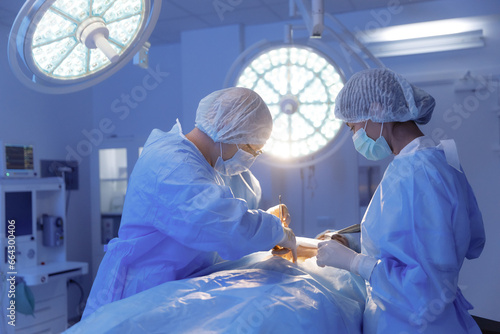 A shot of a nurse handing the surgeon a piece of equipment for the surgery he is performing in a hospital room