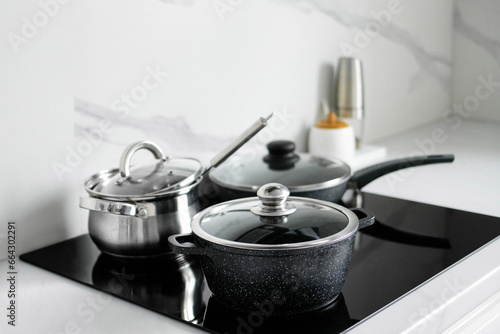 The saucepans stand on an electric induction stove. Modern modernized kitchen in the style of minimalism. Kitchen interior