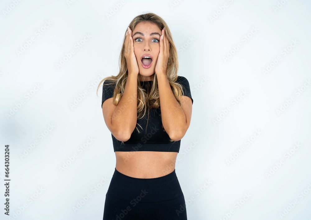 caucasian woman wearing sport clothes with scared expression, keeps hands on head, jaw dropped, has terrific expression. Omg concept caucasian woman wearing sport clothes with scared expression, keeps hands on head, jaw dropped, has terrific expression. Omg concept