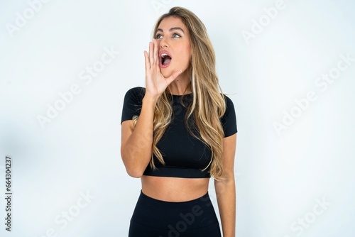 caucasian woman wearing sport clothes shouting and screaming loud to side with hand on mouth. Communication concept.