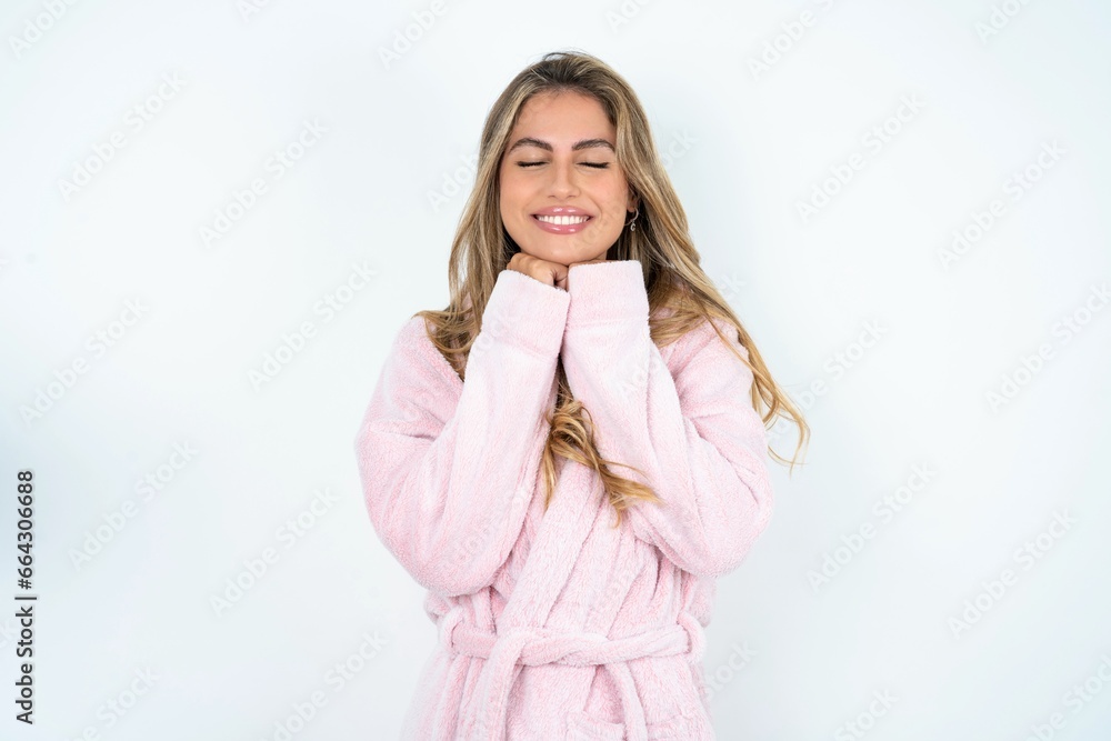 Cheerful Beautiful young woman wearing sleeping gown has shy satisfied expression, smiles broadly, shows white teeth, People emotions Cheerful Beautiful young woman wearing sleeping gown has shy satisfied expression, smiles broadly, shows white teeth, People emotions