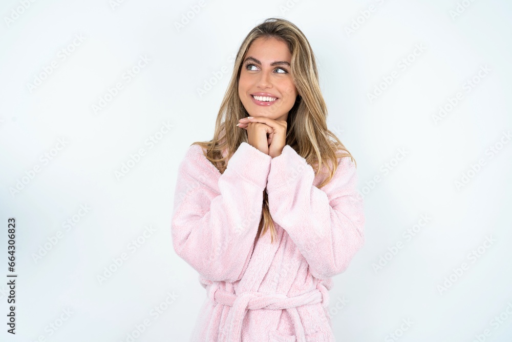 Happy Young beautiful woman anticipates something awesome happen, looks happily aside, keeps hands together near face, has glad expression. Happy Young beautiful woman anticipates something awesome happen, looks happily aside, keeps hands together near face, has glad expression.