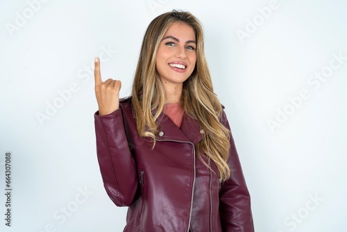 Beautiful young woman wearing jacket smiling and looking friendly, showing number one or first with hand forward, counting down