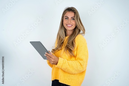 Photo of happy cheerful smart Beautiful caucasian woman wearing yellow jumper hold tablet browsing internet photo