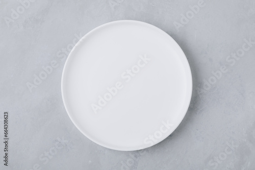White round empty ceramic plate on gray concrete stone background.
