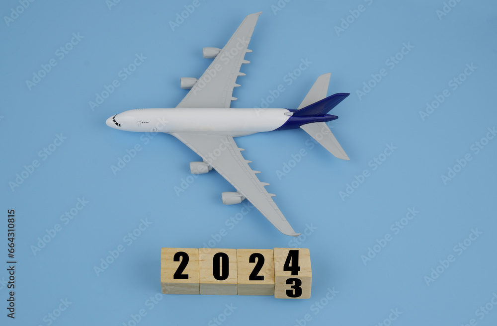 Airplane and wooden cubes with 2023 and 2023 on blue background. Airplane and wooden cubes with 2023 and 2023 on blue background.