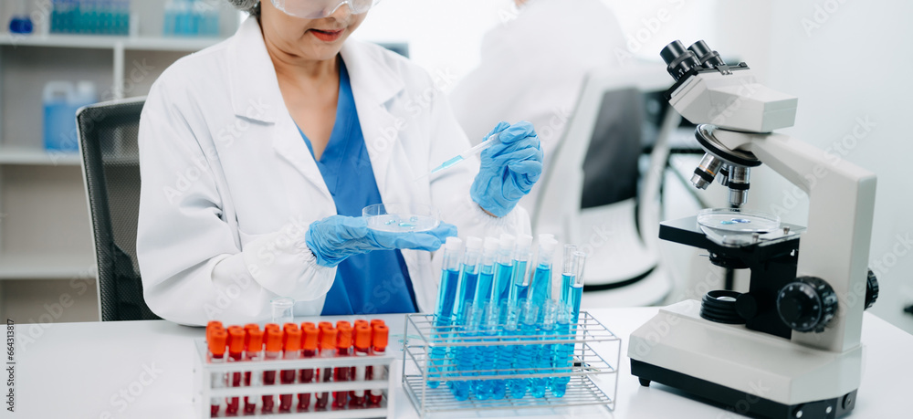 Scientists conducting research investigations in a medical laboratory, a researcher in the foreground is using a microscope in laboratory for medicine. . Scientists conducting research investigations in a medical laboratory, a researcher in the foreground is using a microscope in laboratory for medicine. .