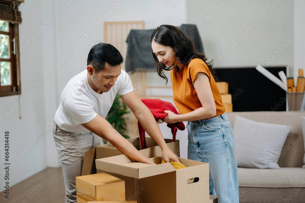 Young couple with big boxes moving into a new house, new apartment for couple, young asian man and woman helping to lift boxes on sofa for the new home, Moving house.. Young couple with big boxes moving into a new house, new apartment for couple, young asian man and woman helping to lift boxes on sofa for the new home, Moving house..