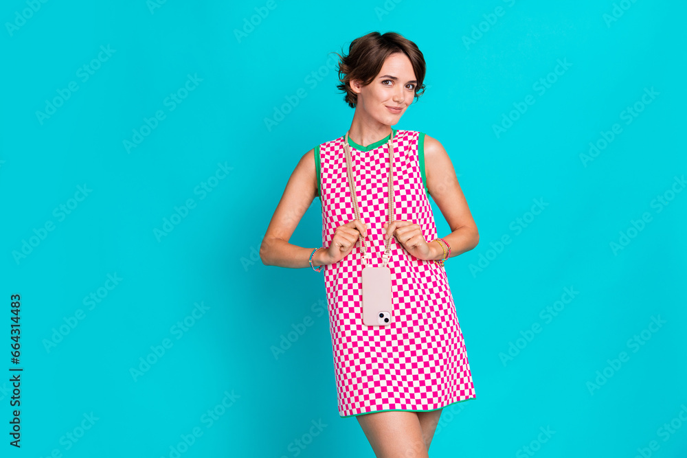 Photo of young girl checkered dress posing candid blogger wear stylish trend hanging phone case isolated on aquamarine color background Photo of young girl checkered dress posing candid blogger wear stylish trend hanging phone case isolated on aquamarine color background