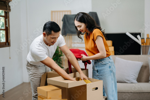 Young couple with big boxes moving into a new house, new apartment for couple, young asian man and woman helping to lift boxes on sofa for the new home, Moving house.. © Nuttapong punna