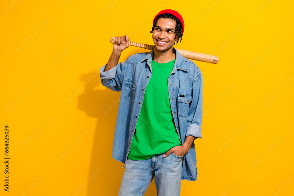 Photo of cheerful cool stylish guy sporty player wear trendy jeans clothes look empty space isolated on yellow color background Photo of cheerful cool stylish guy sporty player wear trendy jeans clothes look empty space isolated on yellow color background