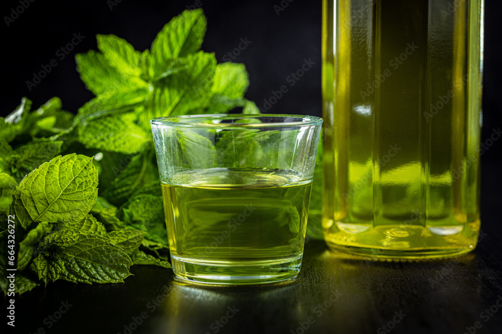 Sweet mint syrup and mint leaves on black table. Sweet mint syrup and mint leaves on black table.