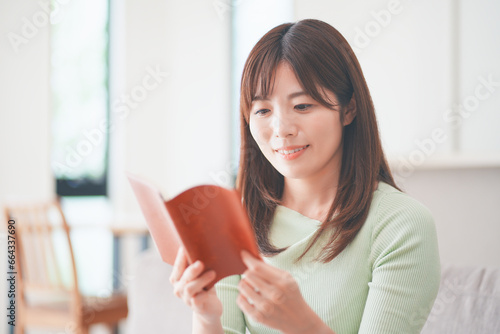 リビングのソファに座って読書する女性