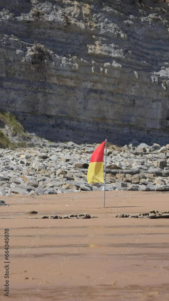 red and yellow flag moves with the wind on the beach red and yellow flag moves with the wind on the beach