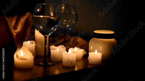 Glasses of wine, burning candles in the dark. The flame is reflected by the glare in the glasses. Romantic dinner, holiday, cozy