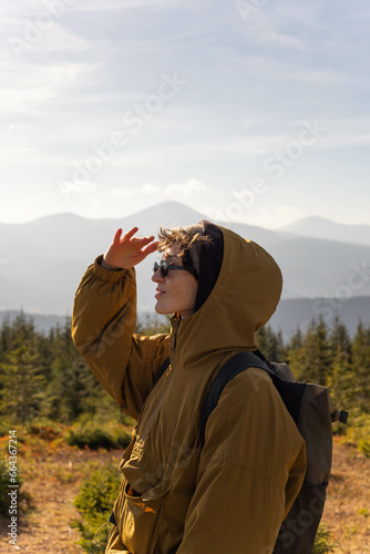 a young woman stands on the background of a mountain range