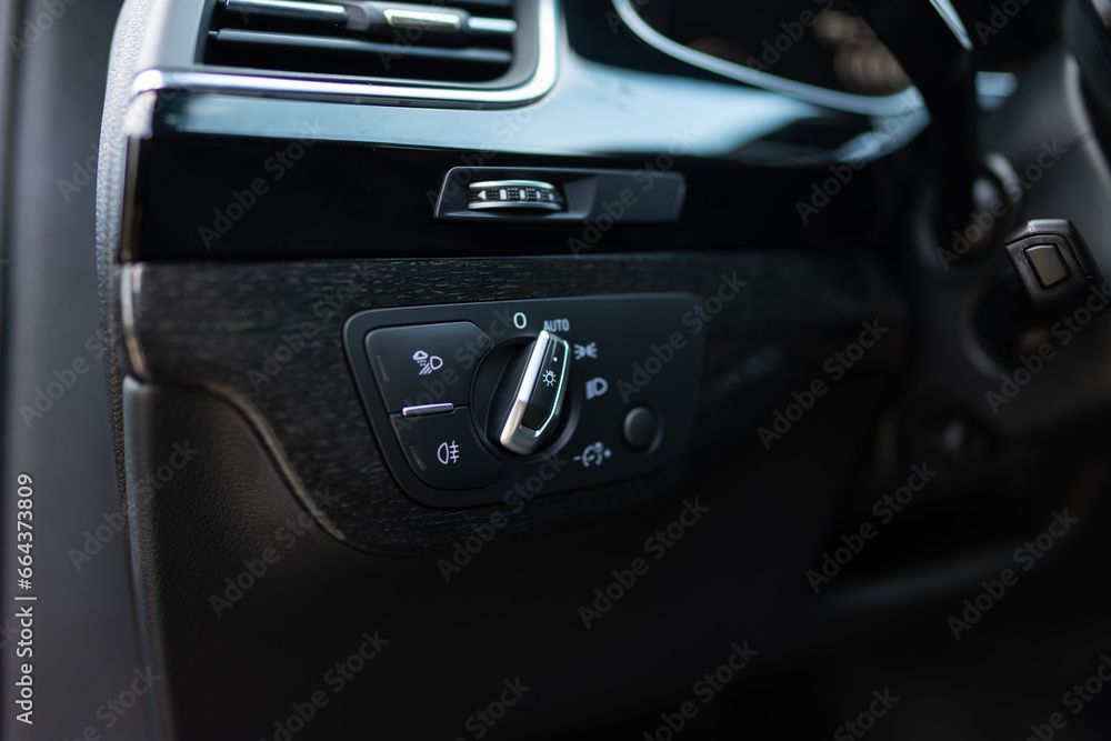 Fog lights switch in luxury automobile. Interior detail of modern car headlights controls being activated in low visibility conditions