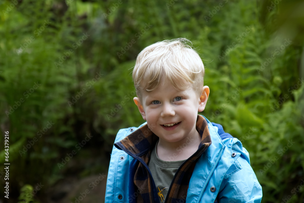 Portrait of a blond boy against a background of green foliage in the park copy space Portrait of a blond boy against a background of green foliage in the park copy space