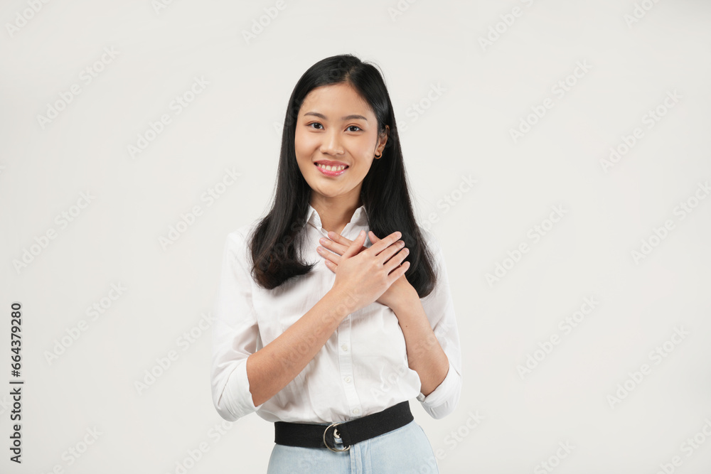 Photo of a beautiful Asian woman holding hands near heart on chest. Isolated on a white background. Photo of a beautiful Asian woman holding hands near heart on chest. Isolated on a white background.
