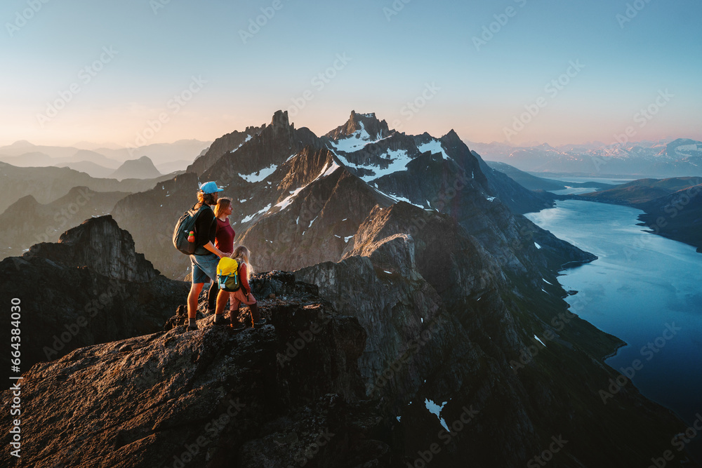 Obraz premium Travel adventures in Norway: family hiking in mountains outdoor parents and child on the top enjoying Kvaloya landscape active healthy lifestyle vacations mother and father with kid eco tourism