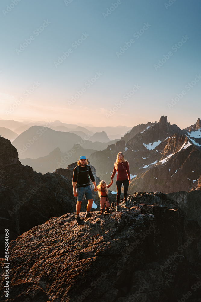 Family parents with child hiking in Norway mountains travel adventure healthy lifestyle outdoor active vacations mother and father with kid climbing Kvaloya summits