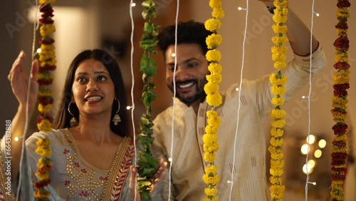 An Indian man and his beautiful wife decorating their house with marigold flowers and lights - an Indian festival. A married couple dressed in ethnic wear for the festival of Diwali. photo